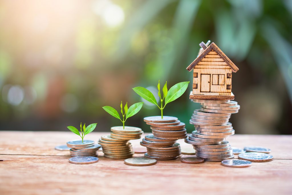 maison sur des pièces d’argent économisées pour représenter le concept de financement par placement hypothécaire et de refinancement de prêt immobilier