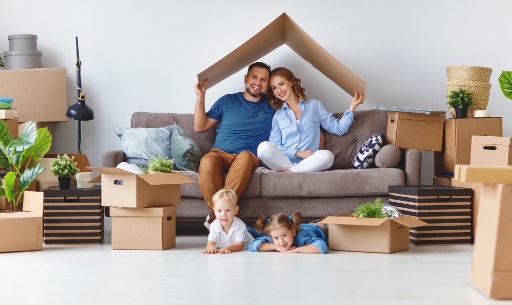 famille joyeuse composée d'une mère, d'un père et d’enfants qui emménagent dans un nouvel appartement et déballent des cartons