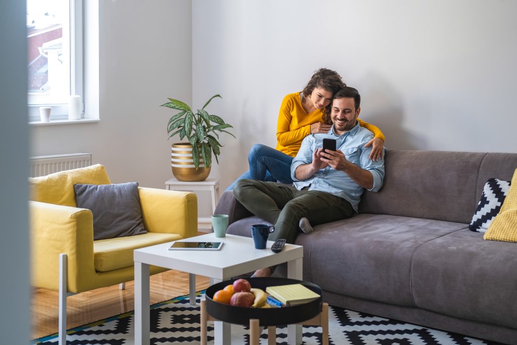 Couple using mobile phone at home stock photo. Positive couple i